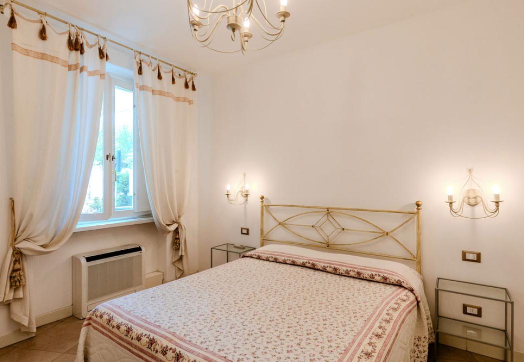 Camera da letto luminosa con letto matrimoniale e lampadari eleganti.