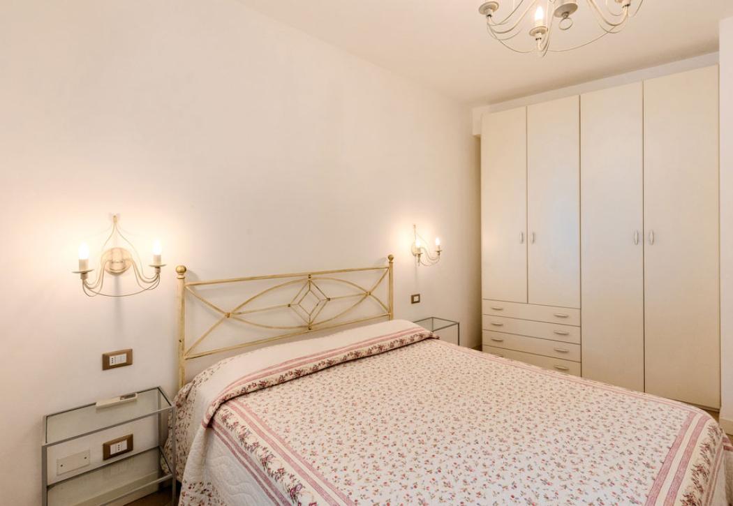 Camera da letto con letto matrimoniale, armadio bianco e luci a parete.