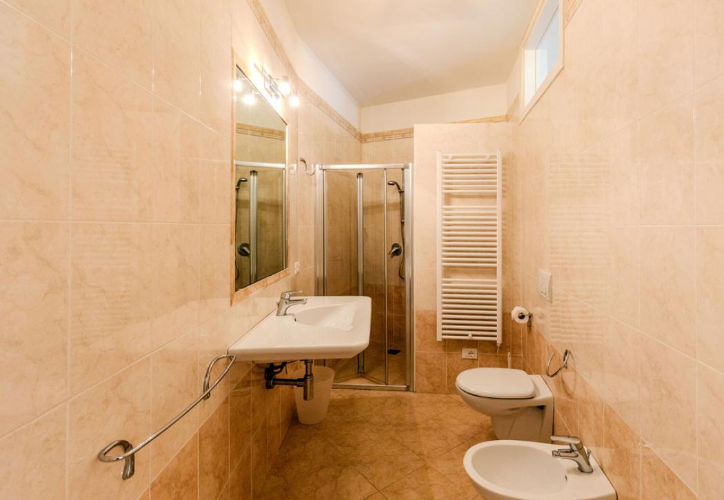 Bathroom with shower, sink, bidet, toilet, and beige tiles.