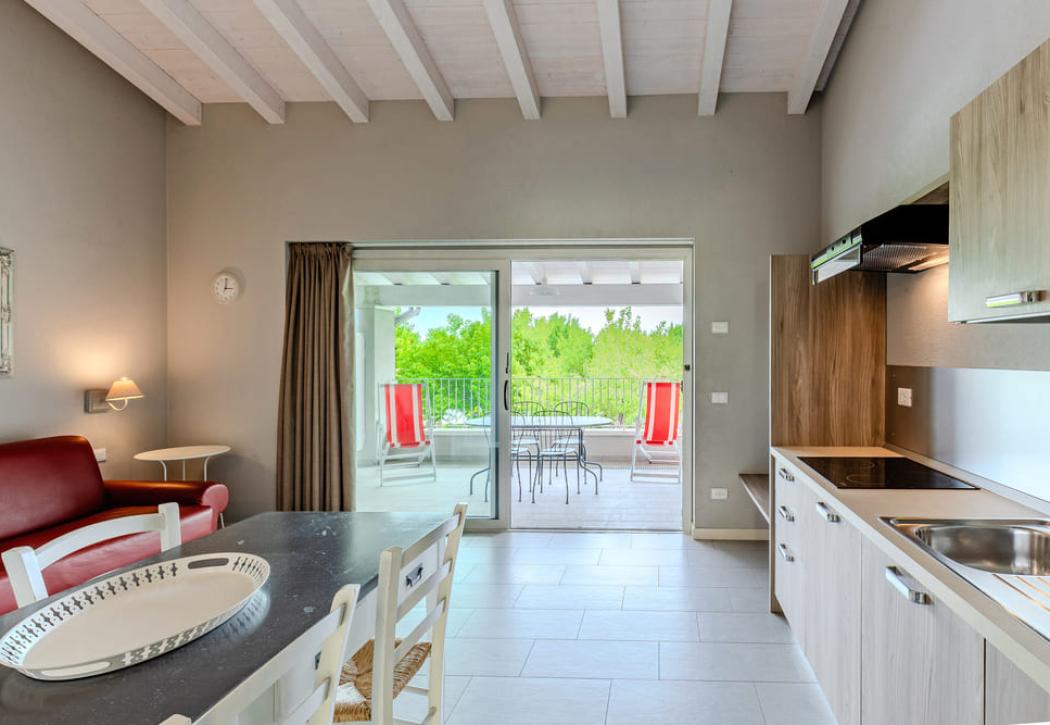 Moderno appartamento con cucina, soggiorno e terrazza con vista verde.