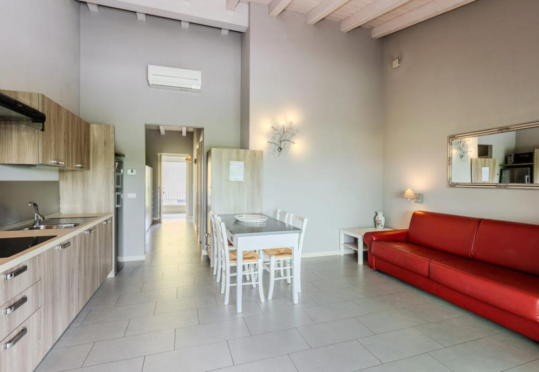 Moderno appartamento con cucina, soggiorno, divano rosso e tavolo da pranzo.