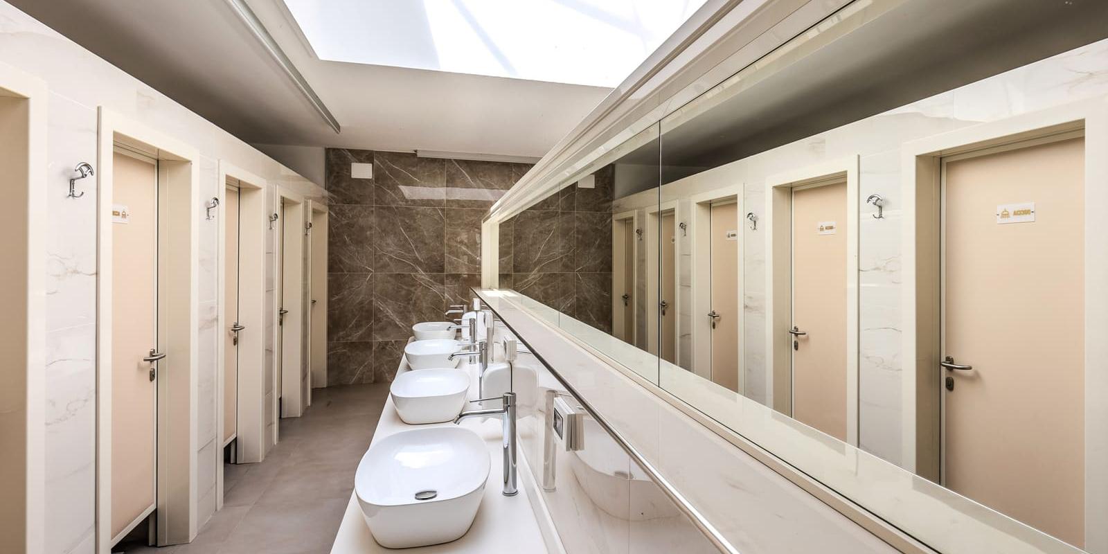 Salle de bain moderne avec lavabos blancs et cabines à portes beiges.