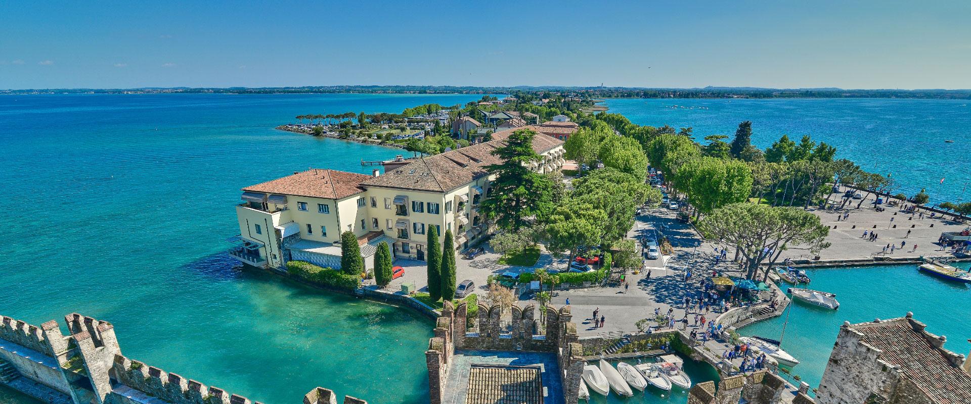 Panoramic view of a coastal village with historic buildings and turquoise waters.