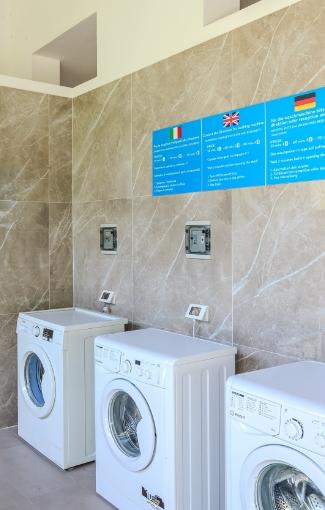 Waschraum mit automatischen Waschmaschinen und mehrsprachigen Anweisungen.