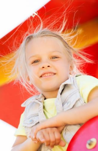 Smiling girl with messy hair against a colorful background.