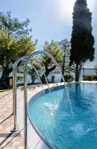 Pool with water jets, surrounded by trees and lake view.