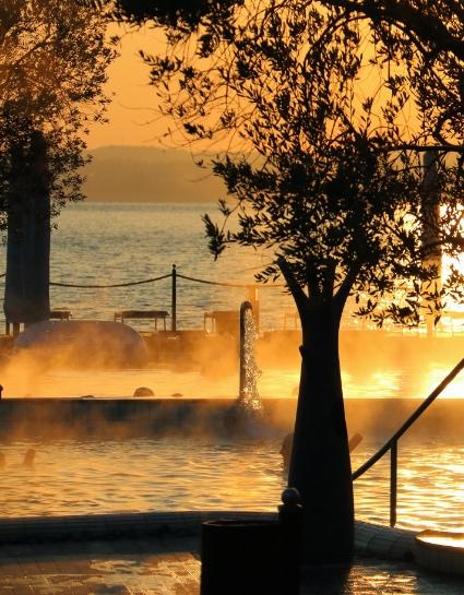 Piscina all'aperto al tramonto con vista sul lago.