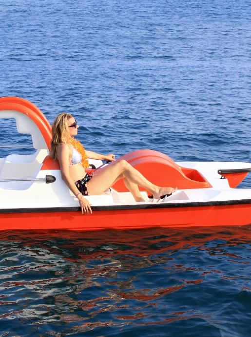 Entspannte Frau auf rotem Tretboot im Meer.