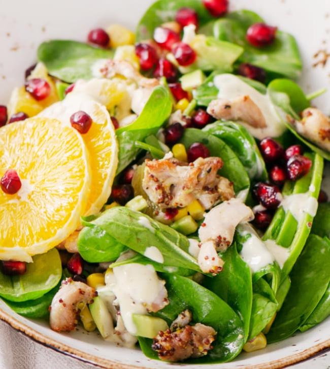 Spinach salad with chicken, oranges, pomegranate, and creamy dressing.