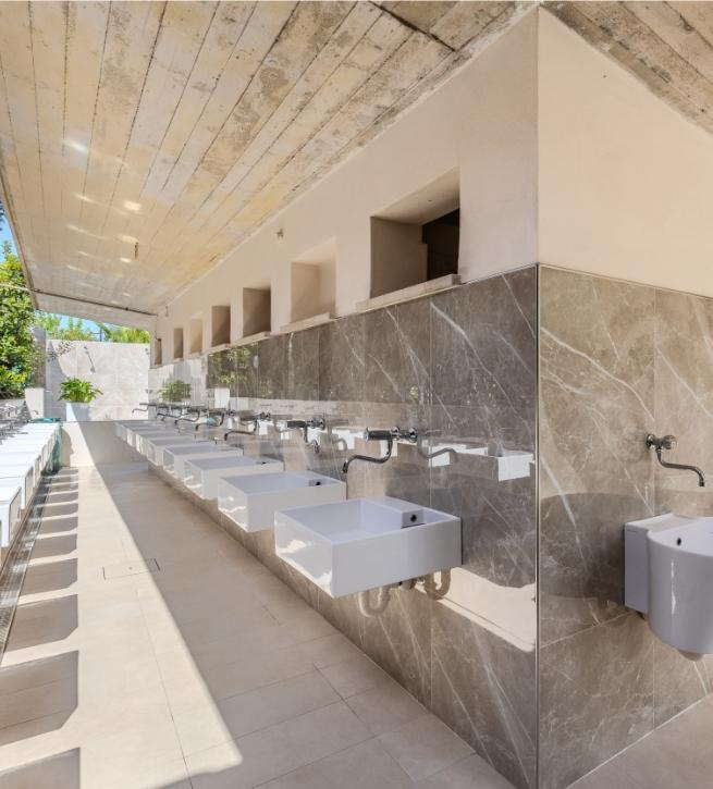 Modernes öffentliches Badezimmer mit weißen Waschbecken und Marmowänden.