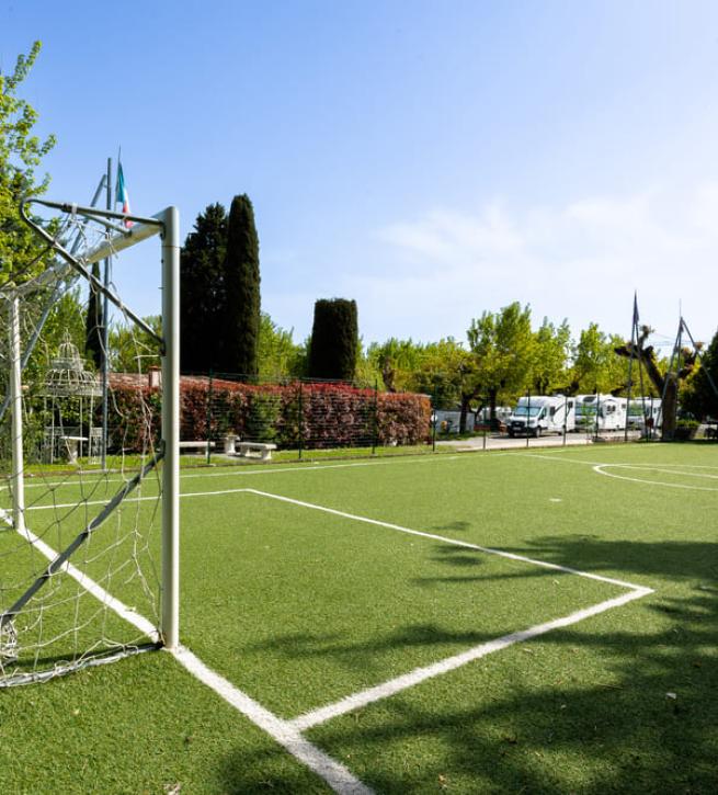 Fußballplatz im Freien mit beschädigtem Netz in einer grünen Umgebung.