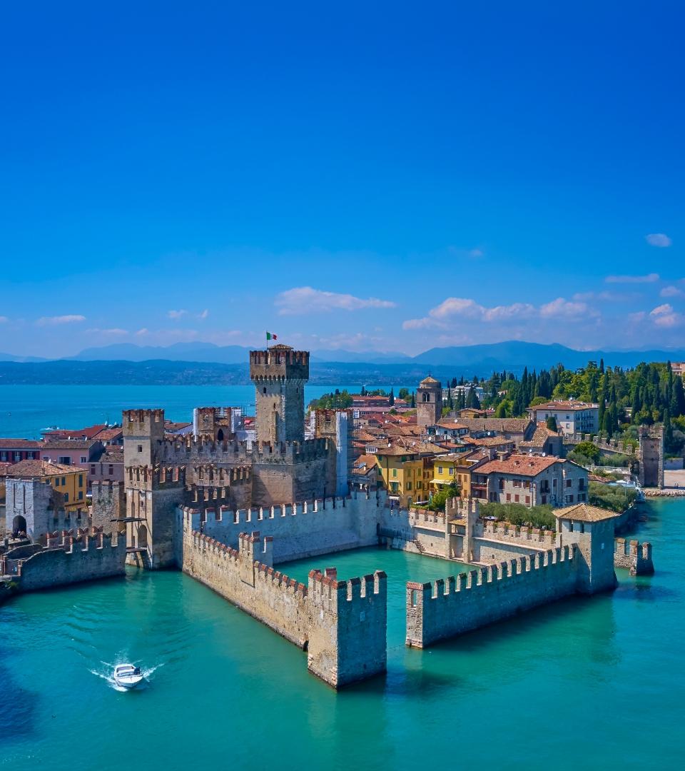 Château médiéval sur le lac avec vue panoramique et bateau dans l'eau.