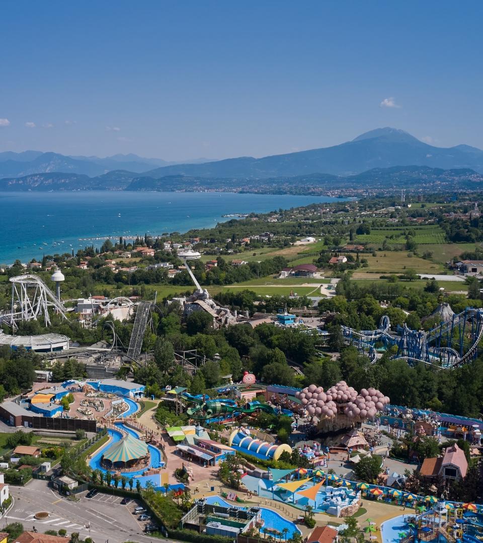 Parco divertimenti vicino al lago, con montagne russe e attrazioni acquatiche.